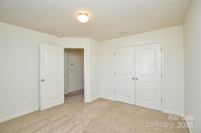 unfurnished bedroom featuring light carpet and a closet