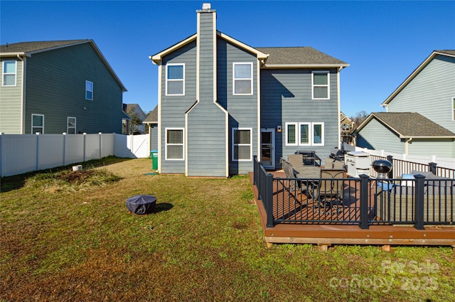 rear view of property with a wooden deck and a lawn