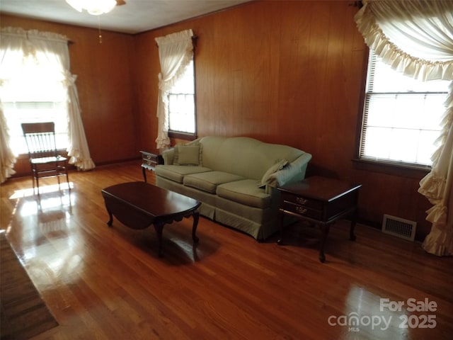 living room featuring plenty of natural light, wood-type flooring, and wood walls