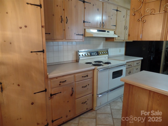 kitchen featuring black refrigerator, white electric range oven, light tile patterned flooring, and decorative backsplash