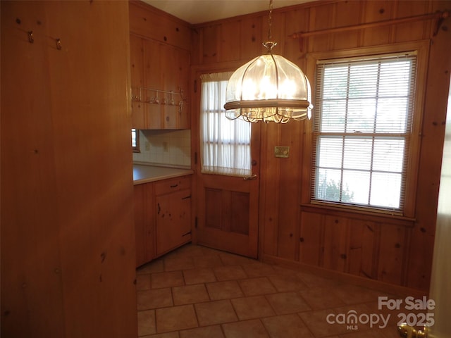 interior space featuring wooden walls, a chandelier, and a healthy amount of sunlight