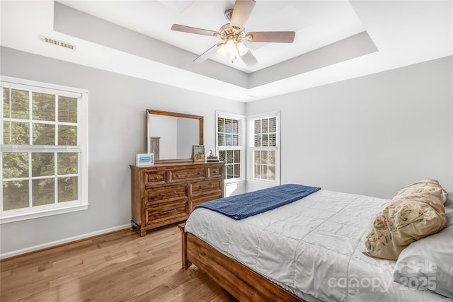 bedroom featuring a tray ceiling, ceiling fan, and light hardwood / wood-style floors