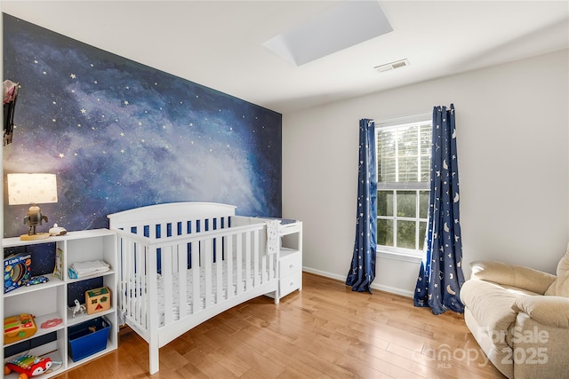 bedroom with hardwood / wood-style floors and a nursery area