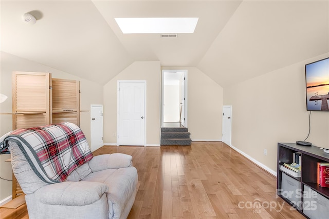 living area with light hardwood / wood-style flooring and vaulted ceiling with skylight