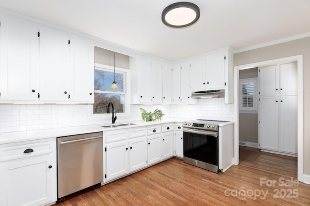 kitchen featuring backsplash, stainless steel appliances, sink, pendant lighting, and white cabinets