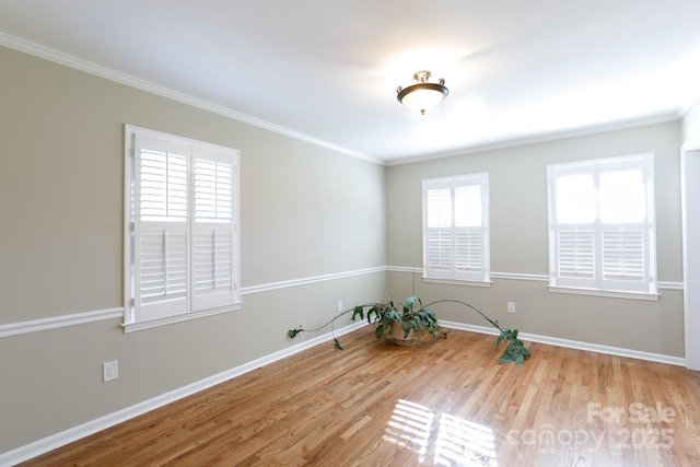 spare room featuring ornamental molding, a healthy amount of sunlight, and wood-type flooring