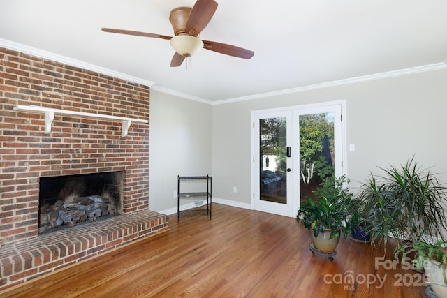 unfurnished living room with hardwood / wood-style floors, french doors, a brick fireplace, ceiling fan, and ornamental molding