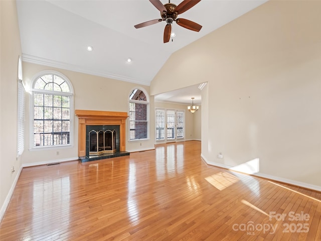 unfurnished living room with ceiling fan with notable chandelier, light hardwood / wood-style floors, vaulted ceiling, and ornamental molding