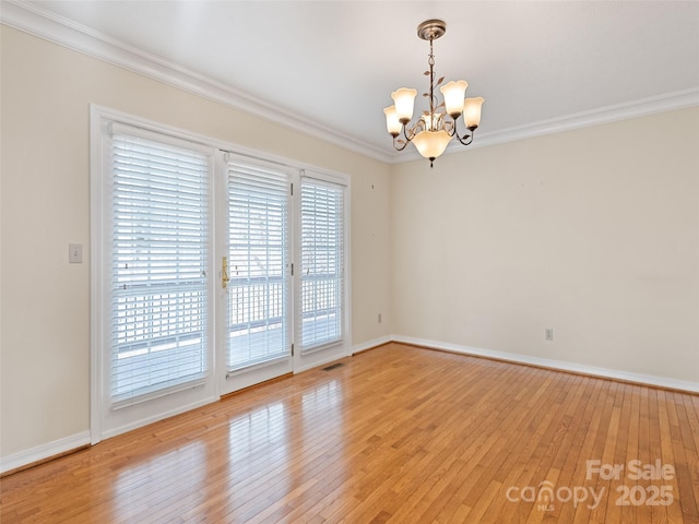 unfurnished room featuring a chandelier, hardwood / wood-style floors, and crown molding