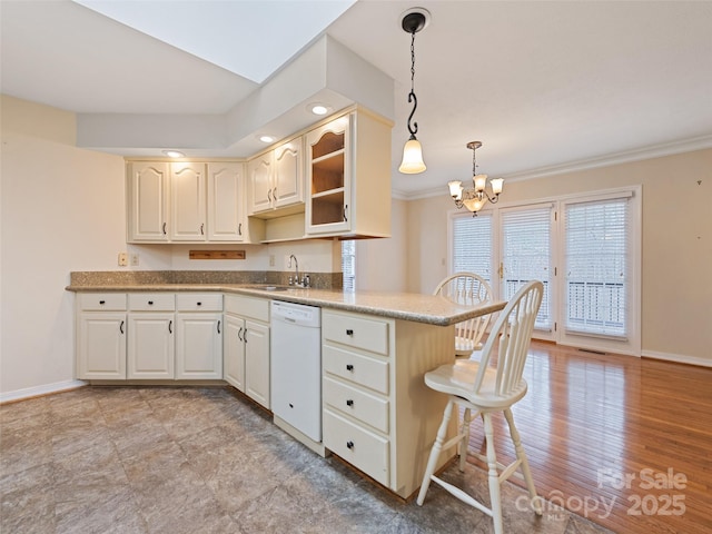 kitchen with sink, hanging light fixtures, kitchen peninsula, white dishwasher, and a chandelier