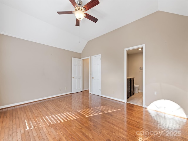 unfurnished bedroom featuring ceiling fan, wood-type flooring, ensuite bathroom, and vaulted ceiling