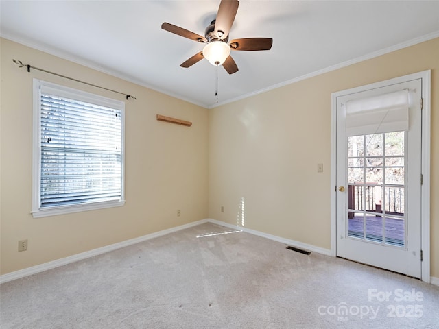 carpeted spare room with ceiling fan, a healthy amount of sunlight, and ornamental molding