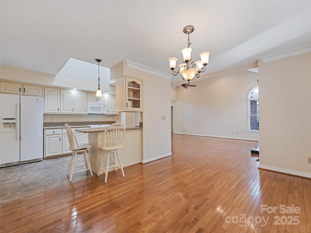 185 Oak Ridge Dr, Clyde, NC 28721 - kitchen with white appliances, a chandelier, light wood-type flooring, decorative light fixtures, and a peninsula
