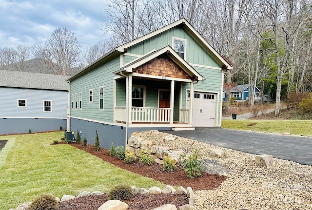 view of front of home with a front yard, a porch, a garage, and cooling unit