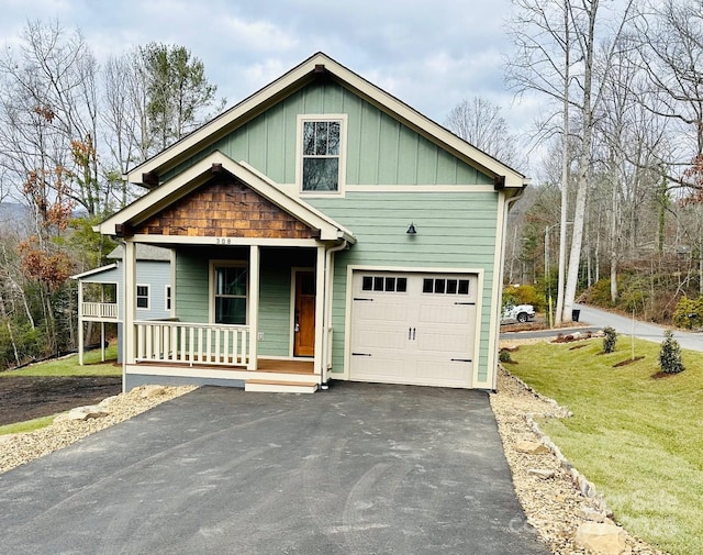 view of front of property featuring covered porch, a garage, and a front lawn