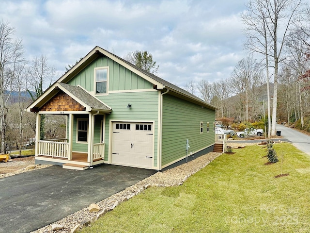 view of front facade with covered porch, a front yard, and a garage