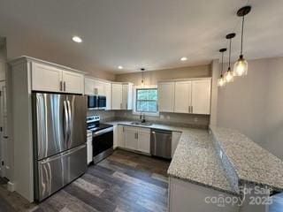 kitchen featuring decorative light fixtures, white cabinetry, light stone counters, kitchen peninsula, and stainless steel appliances