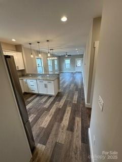 kitchen featuring kitchen peninsula, ceiling fan, dark wood-type flooring, white cabinetry, and hanging light fixtures