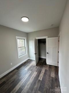 unfurnished bedroom with dark hardwood / wood-style floors and a closet