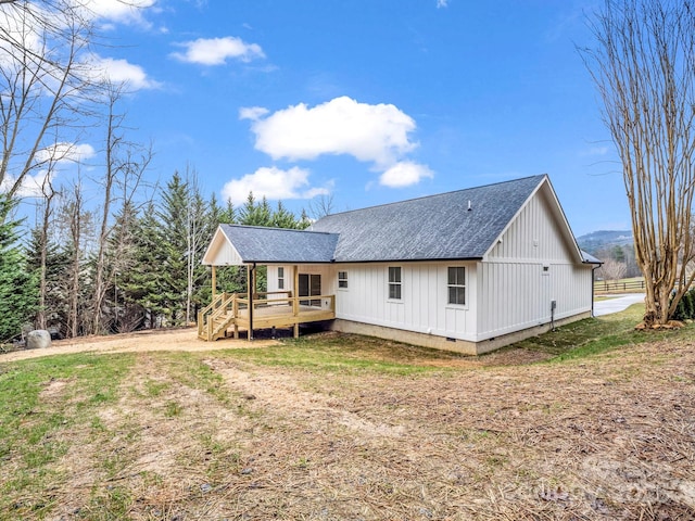 back of property with a deck and a lawn