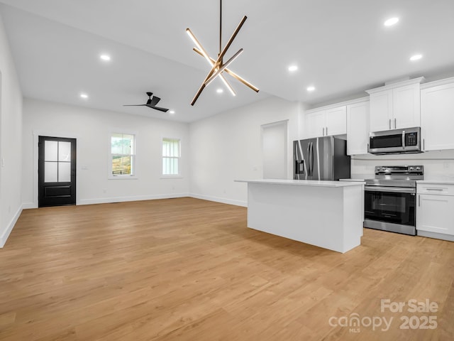 kitchen with white cabinetry, a center island, light hardwood / wood-style floors, ceiling fan with notable chandelier, and appliances with stainless steel finishes