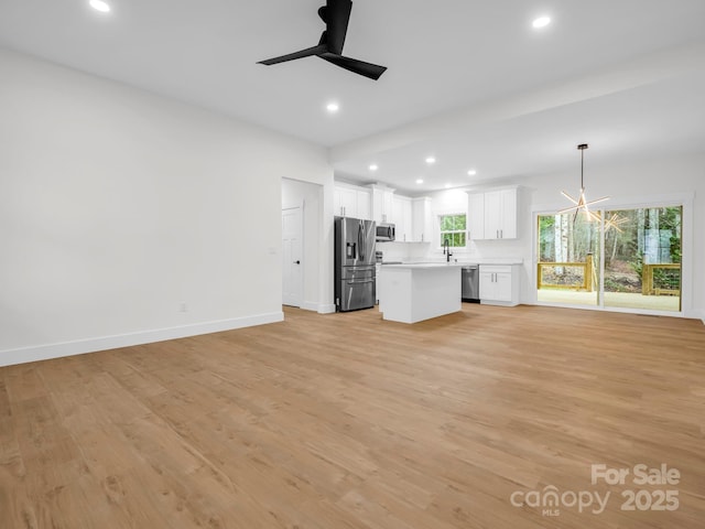 unfurnished living room with light hardwood / wood-style floors and ceiling fan with notable chandelier