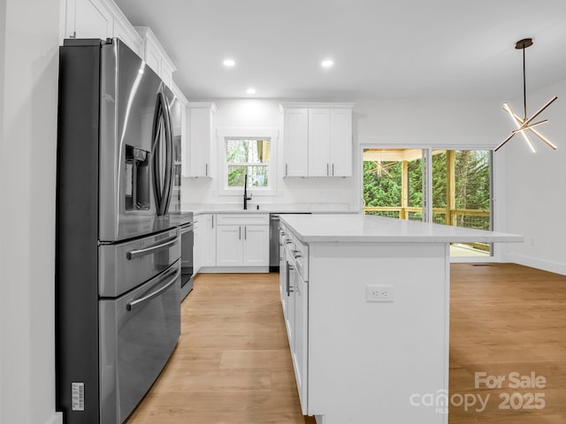 kitchen featuring stainless steel appliances, light hardwood / wood-style flooring, a chandelier, a center island, and white cabinetry