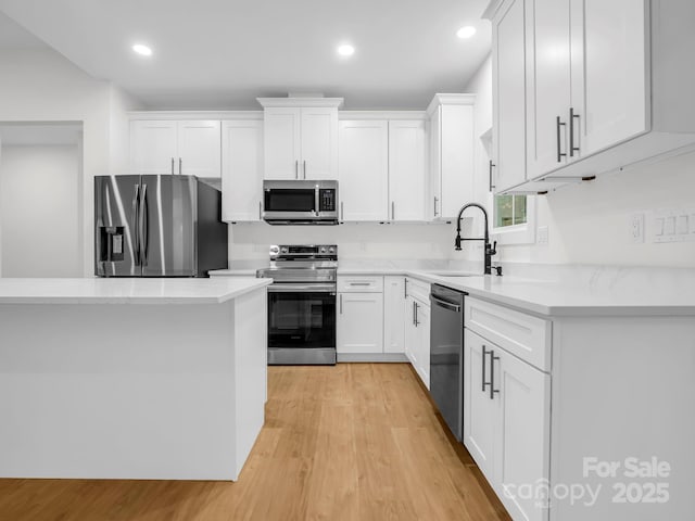 kitchen featuring white cabinetry, sink, appliances with stainless steel finishes, and light hardwood / wood-style flooring