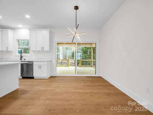 kitchen with a chandelier, white cabinetry, stainless steel dishwasher, and hanging light fixtures