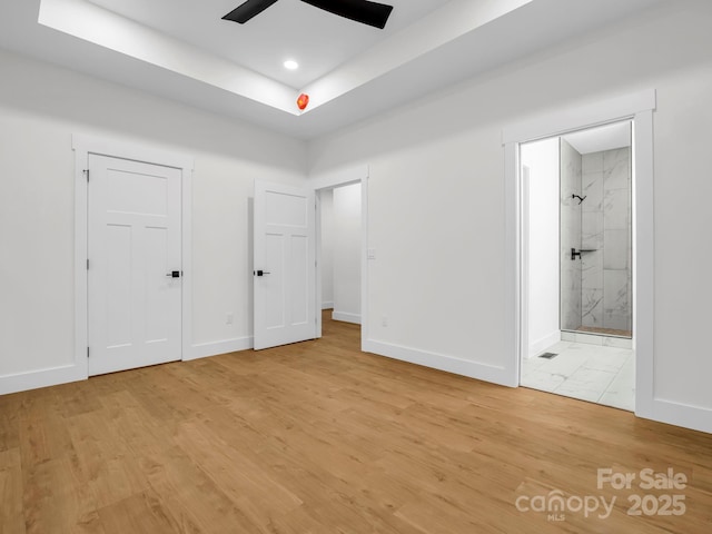 unfurnished bedroom with ensuite bathroom, ceiling fan, and light wood-type flooring