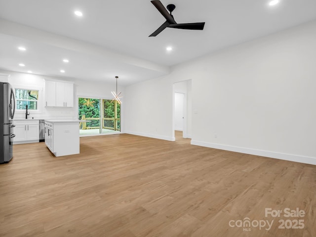 unfurnished living room featuring light hardwood / wood-style flooring, ceiling fan, and sink