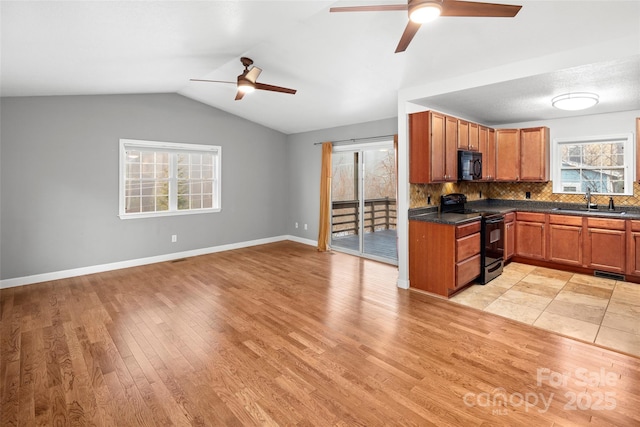 kitchen featuring black appliances, sink, vaulted ceiling, decorative backsplash, and light wood-type flooring