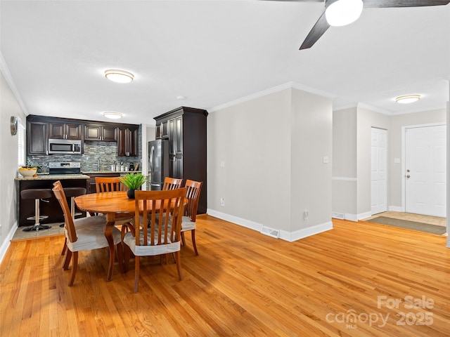 dining room with ceiling fan, sink, light wood-type flooring, and crown molding