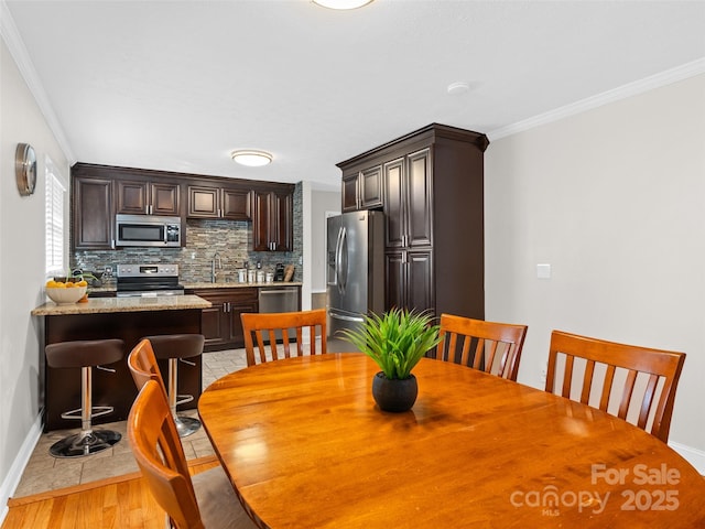 dining space with light wood-type flooring, crown molding, and sink