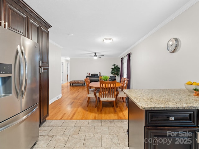 kitchen featuring stainless steel refrigerator with ice dispenser, dark brown cabinetry, light stone counters, and ornamental molding