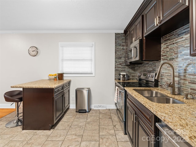 kitchen featuring sink, stainless steel appliances, crown molding, a breakfast bar area, and dark brown cabinets