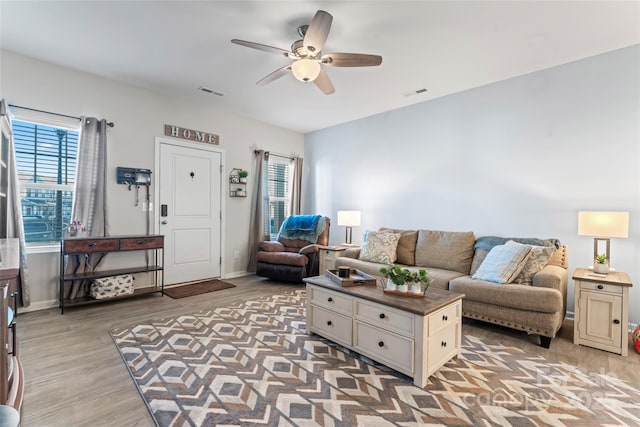 living room with ceiling fan, plenty of natural light, and light hardwood / wood-style floors