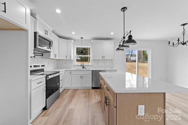 kitchen featuring light wood-style flooring, stainless steel appliances, a sink, and light countertops