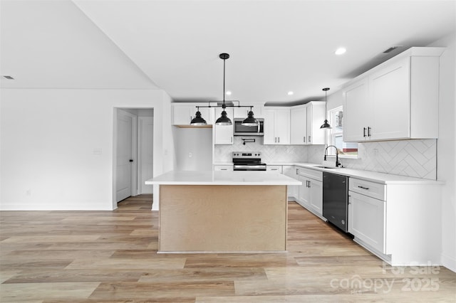 kitchen featuring light wood finished floors, appliances with stainless steel finishes, hanging light fixtures, light countertops, and a sink