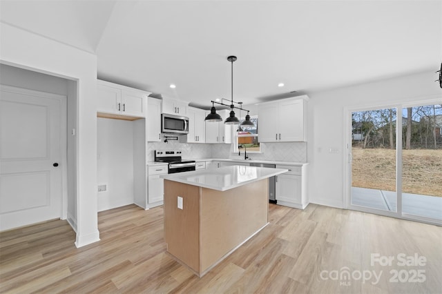 kitchen with appliances with stainless steel finishes, light wood-style floors, light countertops, and a sink