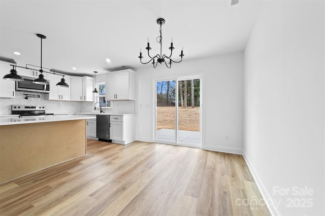 kitchen featuring a sink, light wood-style floors, light countertops, appliances with stainless steel finishes, and tasteful backsplash