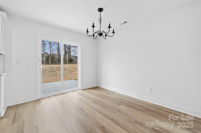 unfurnished dining area featuring an inviting chandelier, baseboards, visible vents, and light wood-style floors