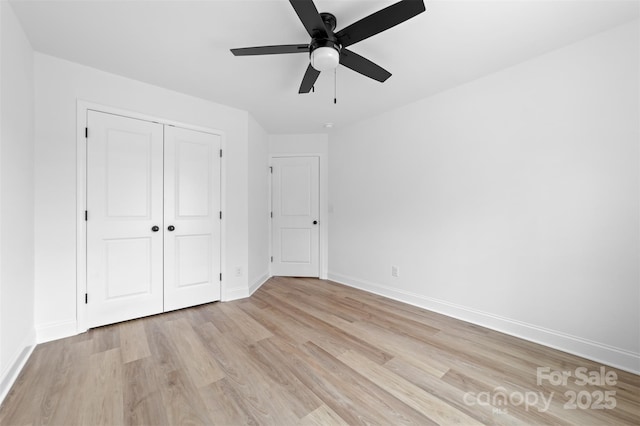 unfurnished bedroom with light wood-type flooring, ceiling fan, baseboards, and a closet