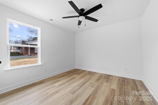 empty room with baseboards, visible vents, ceiling fan, and wood finished floors