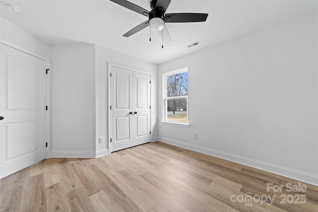 unfurnished bedroom with light wood-style floors, visible vents, baseboards, and a ceiling fan