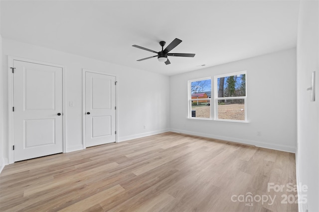 spare room with a ceiling fan, light wood-style flooring, and baseboards