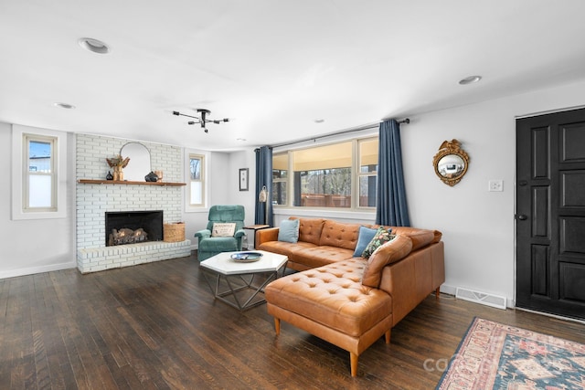 living room featuring a brick fireplace and dark wood-type flooring