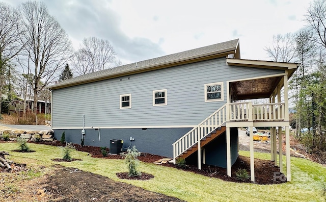 rear view of house featuring central AC unit and a lawn