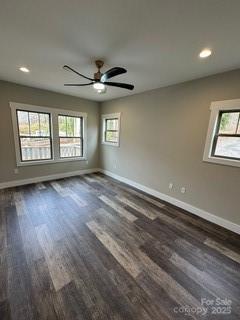 empty room featuring a healthy amount of sunlight, ceiling fan, and dark wood-type flooring