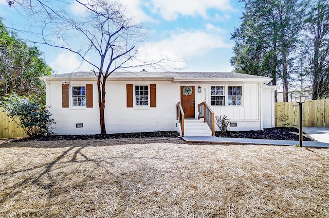 view of front of property with fence, a shingled roof, crawl space, board and batten siding, and brick siding